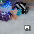 1:12 scale miniature bear cub doll in beige and orange flocked finish, sitting on a white rug by wrapped gifts