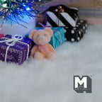 1:12 scale miniature bear cub doll in beige and orange flocked finish, sitting on a white rug by wrapped gifts