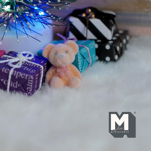 1:12 scale miniature bear cub doll in beige and orange flocked finish, sitting on a white rug by wrapped gifts