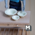 1:12 scale miniature metal bowls with beaded rim in yellow, set of 3 nesting sizes, on a wood table with a poseable figure