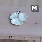 1:12 scale miniature 3 compartment scalloped dish in cream with a silver center handle, shown on a wood table