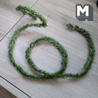 1:12 scale miniature pine needle garland in green, style E, shown coiled on a wood surface