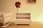 1:12 scale miniature bathroom storage cabinet in white with open shelves and 2 drawers, shown with a vase of roses