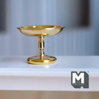 1:12 scale miniature metal pedestal cake stand, tall, in shiny gold with a turned stem, shown on a white shelf