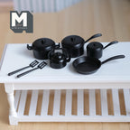 1:12 scale miniature metal cookware set in black with pots, pan, kettle and spatulas, set of 7, shown on a white table