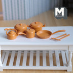 1:12 scale miniature metal cookware set in orange with pots, pan, kettle and spatulas, set of 7, shown on a white table