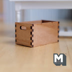 1:12 scale miniature wood storage crate with handles in natural wood with finger joint corners, shown on a wood floor