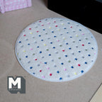 1:12 scale miniature multicolor dot round shag rug in white with a stitched edge, shown on a floor