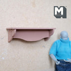 1:12 scale miniature wood scalloped wall shelf kit in dusty pink, shown assembled on a wall beside a jointed figure
