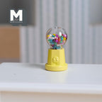 1:12 scale miniature metal tabletop gumball machine in pastel yellow with colorful gumballs, non working, shown on a white table