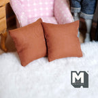 1:12 scale miniature sofa cushions in rust brown, set of 2 square pillows, shown on a white fluffy rug by a pink armchair