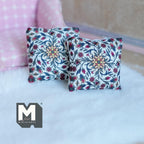 1:12 scale miniature floral print throw pillows in red and white with a vine and flower pattern, set of 2, on a white rug