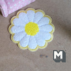 1:12 scale miniature daisy flower shag rug with a yellow border, white petals and yellow center, shown on the floor
