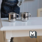 1:12 scale miniature metal coffee mugs in shiny silver with black coffee lettering, set of 2, shown on a white table