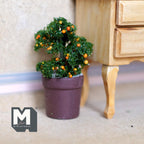 1:12 scale miniature potted orange tree with green foliage and tiny orange fruit in a dark brown pot, beside a wood dresser