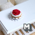 1:12 scale miniature berry cake on lace plate in red and white, topped with red berries and cream, on a white table