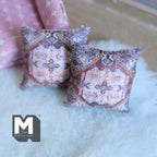 1:12 scale miniature tile print throw pillows in pink with an ornate brown and cream pattern, set of 2, on a white rug