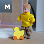 1:12 scale miniature wood duck pull toy in yellow with orange wheels and beak, shown beside a doll