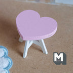 1:12 scale miniature wood heart table kit in pink with white legs, shown assembled on a tan floor