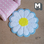 1:12 scale miniature daisy flower shag rug with a blue border, white petals and yellow center, shown on the floor