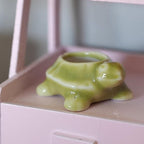 1:12 scale miniature ceramic turtle planter in glossy green with an open shell, shown on a pink shelf