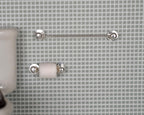 1:12 scale miniature toilet roll holder and towel bar in silver, set of 2, shown mounted on a gray tiled bathroom wall
