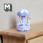 1:12 scale miniature carousel merry go round in light purple with hanging white horses, shown on a wood dresser