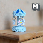 1:12 scale miniature carousel merry go round in light blue with hanging white horses, shown on a wood dresser
