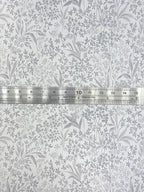 1:12 scale miniature botanical peel and stick wallpaper in light gray with a dense leaf and flower print, shown with a ruler