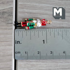 1:12 scale miniature metal nutcracker soldier ornament in green and red with a hanging loop, shown lying beside a ruler