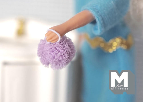 1:12 scale miniature bath sponge pouf with loop in lavender, shown hanging from a doll's hand
