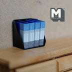 1:12 scale miniature desk file holder in black with 4 blue binders, shown on a wood dresser