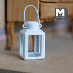 1:12 scale miniature metal camping lantern in white with a wire carry handle and open sides, shown on the floor