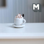 1:12 scale miniature hot chocolate with whipped cream and cookie in a white cup on a saucer, shown on a white table