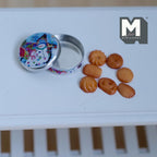 1:12 scale miniature butter cookie tin with 7 cookies, round silver tin with a colorful pattern lid, shown open on a white table