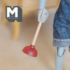 1:12 scale miniature toilet plunger with red rubber cup and wood handle, held by a posable figure