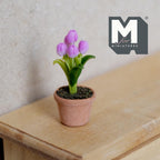 1:12 scale miniature potted tulips in lilac in a clay pot with green leaves, shown on a wood dresser