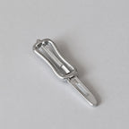 1:12 scale miniature metal vegetable peeler in silver with a slotted blade, shown on a white surface