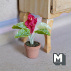 1:12 scale miniature potted red calla lily in a clay pot with speckled green leaves, shown on the floor beside furniture