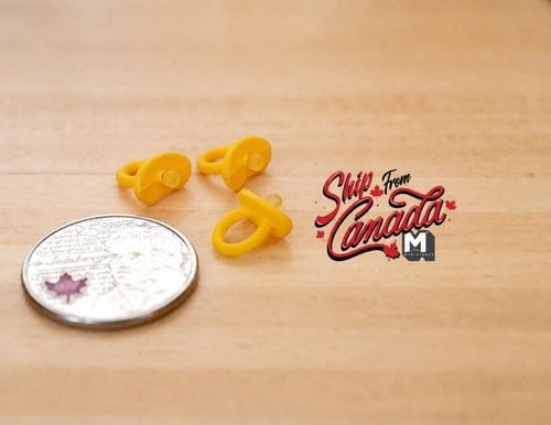 1:12 scale miniature baby pacifiers in yellow, set of 3, shown beside a coin for scale on a wood surface