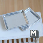 1:12 scale miniature metal baking sheet pans in silver, set of 2, rimmed rectangular trays on a white table