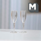 1:12 scale miniature champagne flutes in clear, style A, set of 2, slim tapered bowls on straight stems, on a white table