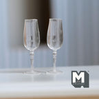 1:12 scale miniature champagne flutes in clear, style B, set of 2, tall bowls on decorative stems, on a white table