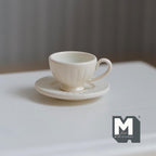 1:12 scale miniature coffee cup and ribbed saucer in cream, set of 2, fluted cup with handle on a white table