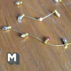 1:12 scale miniature multicolor light bulb bead chain on gold string, non working, shown on a wood surface