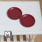 1:12 scale miniature flat dinner plates in red, set of 2, plain round with a narrow rim, on a white table