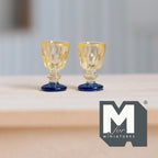 1:12 scale miniature goblets in amber and blue, set of 2, amber bowls on blue stems, shown on a wood table