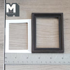 1:12 scale miniature ornate picture frame with mat in dark brown, large, beaded inner edge, shown with a white mat and ruler