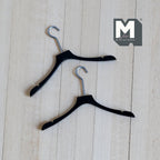 1:12 scale miniature clothes hangers in black with silver metal hooks, set of 2, shown on a light wood surface