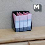 1:12 scale miniature desk file holder in black with 4 pink binders, shown on a wood dresser
